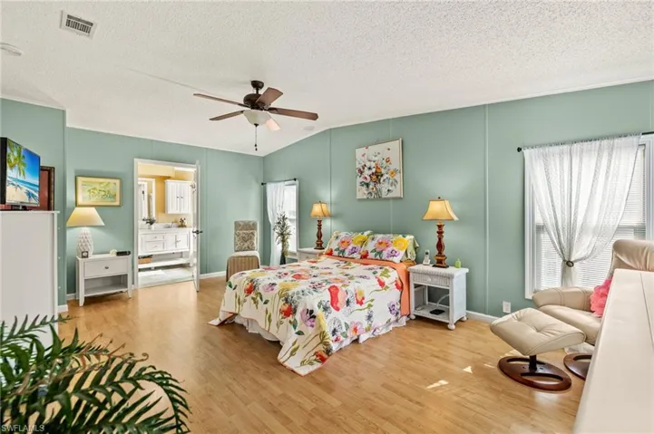 Bedroom with ceiling fan, hardwood / wood-style floors, a textured ceiling, and ensuite bath