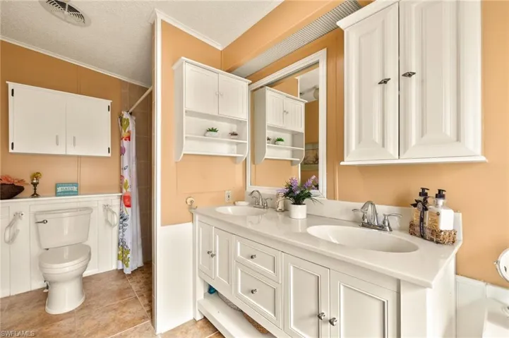 Bathroom with tile patterned floors, toilet, crown molding, a textured ceiling, and vanity