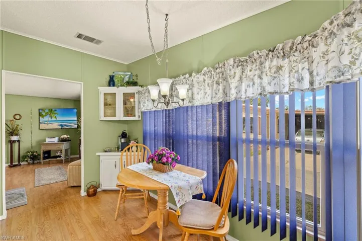 Dining room featuring crown molding, an inviting chandelier, a textured ceiling, and light wood-type flooring