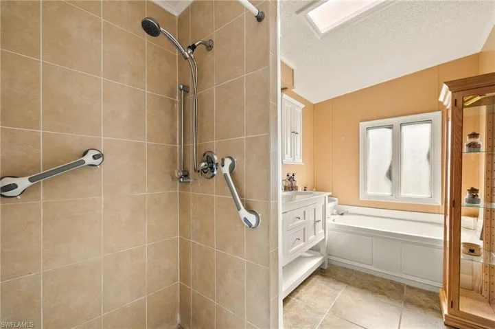 Bathroom with vanity, a textured ceiling, and plus walk in shower