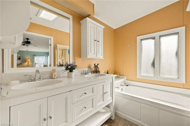 Bathroom with vanity, plenty of natural light, a washtub, and a textured ceiling