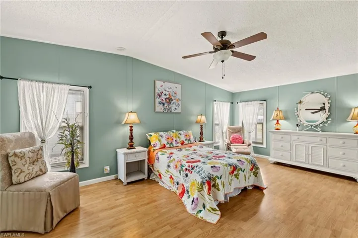 Bedroom with ceiling fan, lofted ceiling, light hardwood / wood-style floors, and a textured ceiling