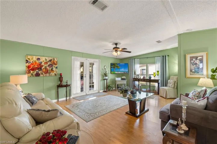 Living room with french doors, ceiling fan, light hardwood / wood-style flooring, and a textured ceiling