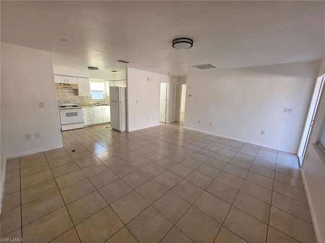 Unfurnished living room with light tile patterned floors and baseboards