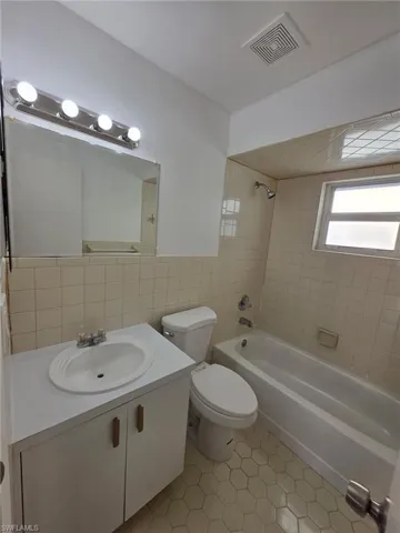 Full bathroom featuring vanity, tile walls,  shower combination, and light tile patterned floors