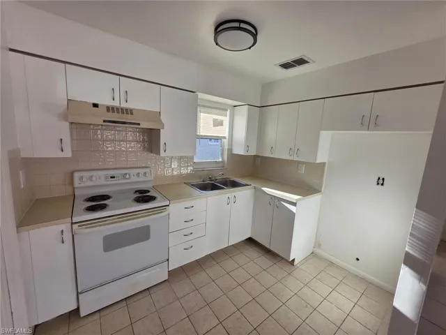 Kitchen with electric stove, white cabinetry, light countertops, tasteful backsplash, and light tile patterned floors