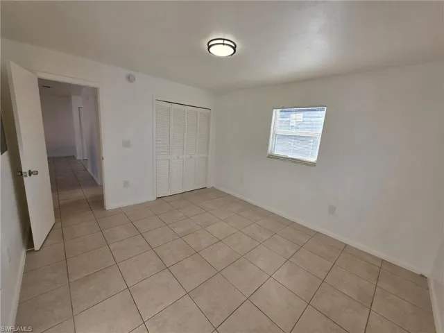 Unfurnished bedroom with a closet and light tile patterned flooring