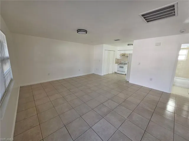 Unfurnished living room featuring light tile patterned floors and baseboards