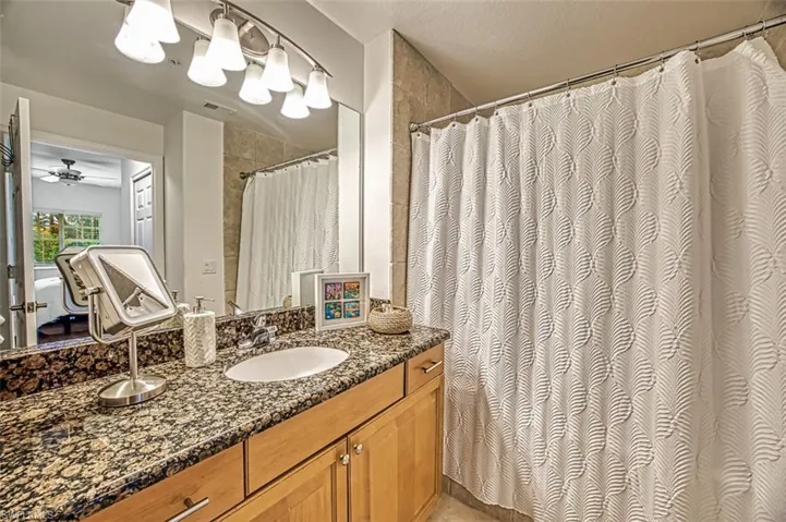 Bathroom featuring walk in shower, vanity, a textured ceiling, and ceiling fan