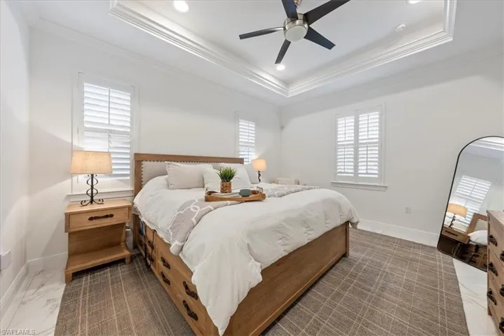 Bedroom with a raised ceiling, crown molding, baseboards, marble finish floors, and recessed lighting