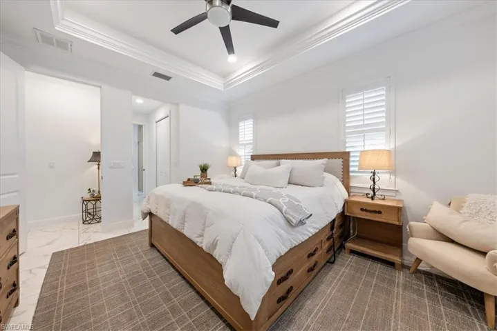 Bedroom featuring ornamental molding, a tray ceiling, a closet, a ceiling fan, and baseboards