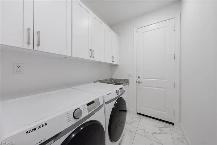 Laundry area with washing machine and clothes dryer, cabinet space, sink