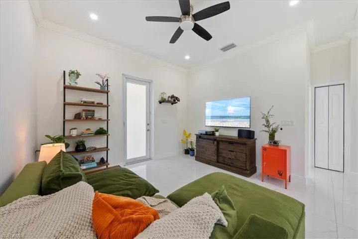 lighting, ornamental molding, ceiling fan, and light marble finish flooring