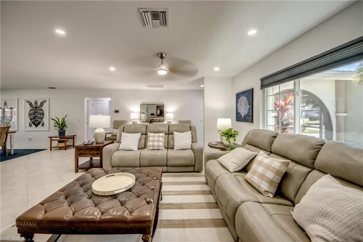 Living room featuring ceiling fan, light tile patterned flooring, and a healthy amount of sunlight