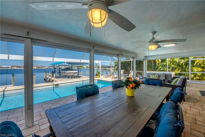 Sunroom featuring a water view, ceiling fan, and a swimming pool