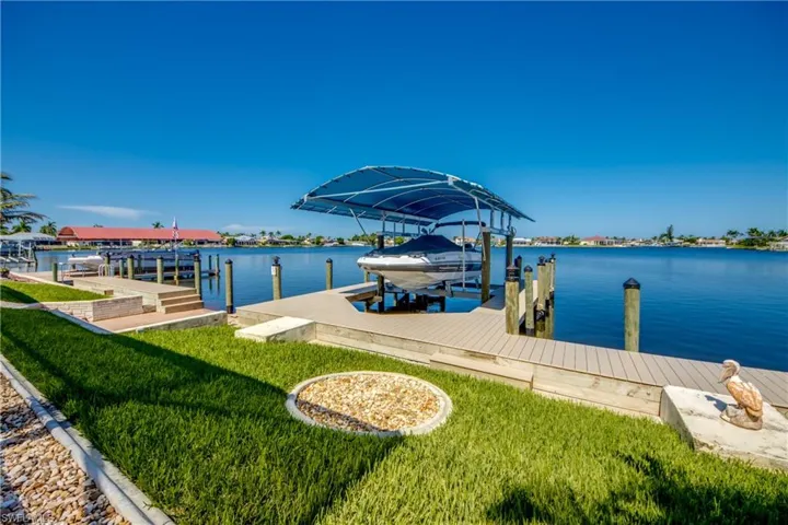 Dock area featuring a fire pit, a water view, and a lawn