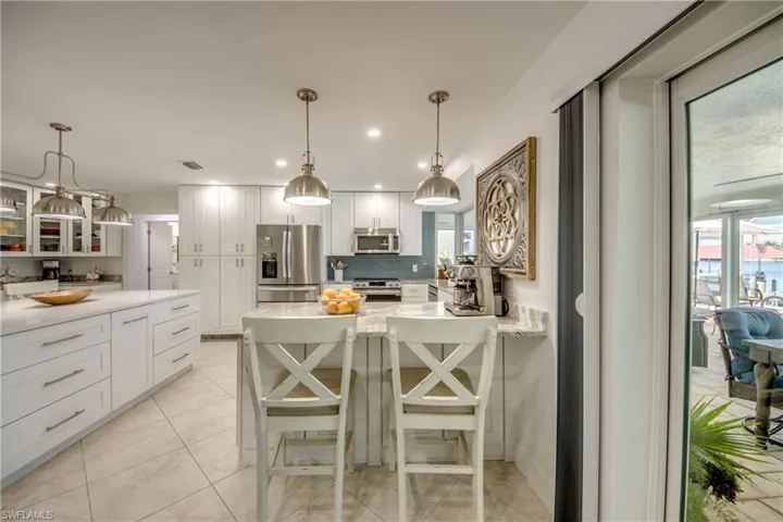 Kitchen featuring appliances with stainless steel finishes, white cabinetry, backsplash, and pendant lighting