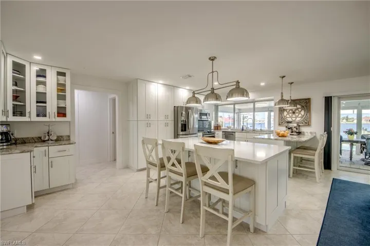Kitchen featuring a breakfast bar area, decorative light fixtures, light tile patterned floors, appliances with stainless steel finishes, and white cabinetry