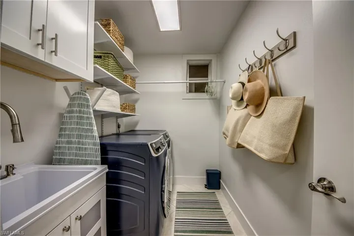 Laundry room featuring light tile patterned flooring, cabinets, washing machine and clothes dryer, and sink