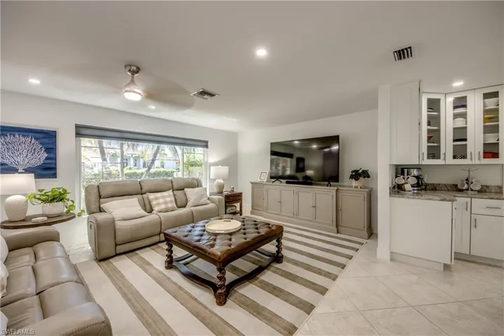 Living room with bar area, ceiling fan, and light tile patterned floors