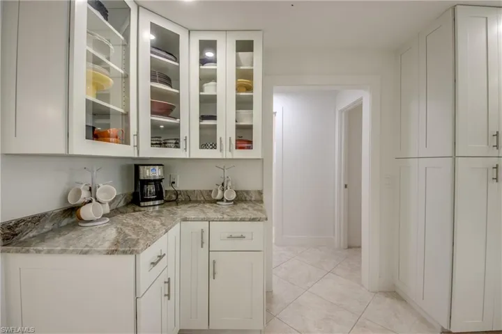 Kitchen with white cabinetry, light stone counters, and light tile patterned floors