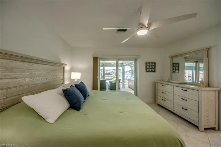 Tiled bedroom with multiple windows, access to exterior, and ceiling fan