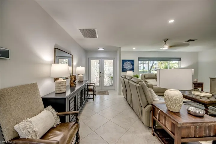 Tiled living room with ceiling fan and french doors