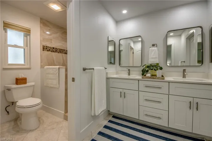 Bathroom with a shower, tile patterned flooring, toilet, and vanity