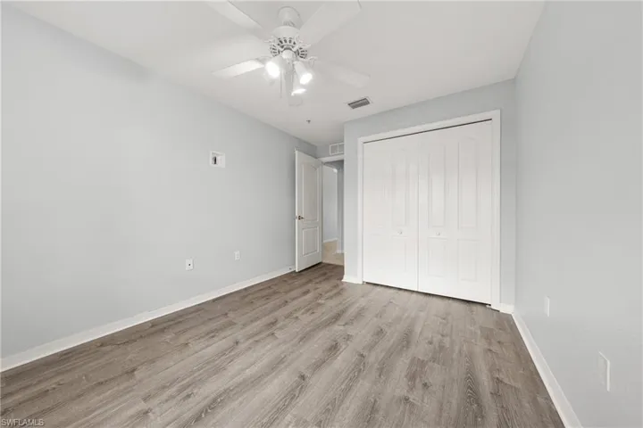 Spacious room featuring wood-finish flooring, light gray wall paint, and white trim