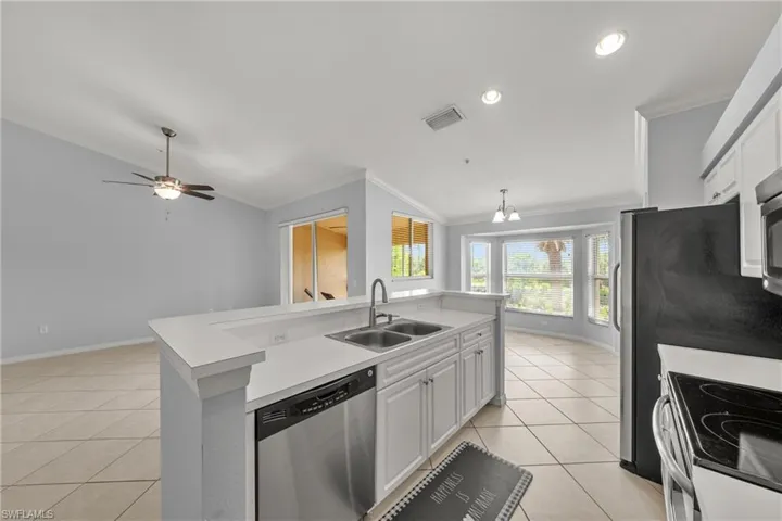 Kitchen island featuring a double-basin sink, stainless steel dishwasher, and white cabinetry