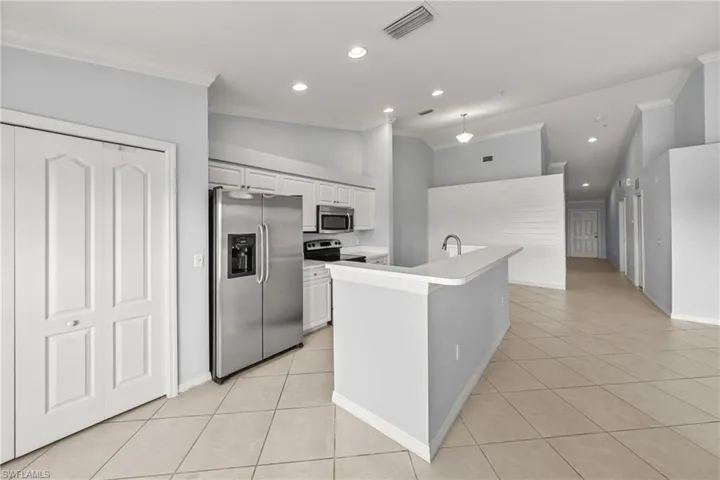 Kitchen with white cabinetry, stainless steel appliances, and a breakfast bar island featuring a single-basin sink
