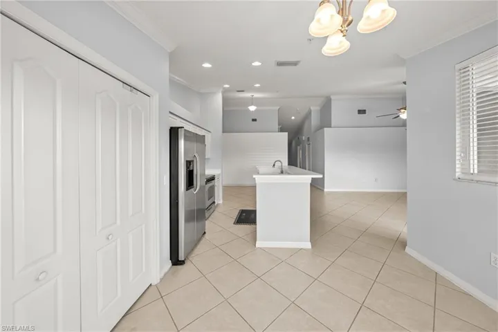 Open concept living area featuring diagonal tile flooring, a kitchen island with sink, stainless steel appliances, and ceiling-mounted light fixtures