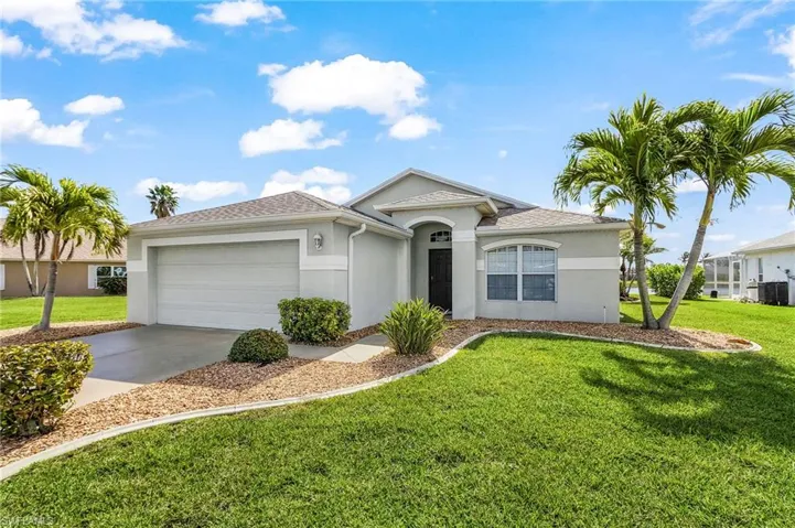 Ranch-style home featuring a front yard, an attached garage, stucco siding, driveway, and a shingled roof