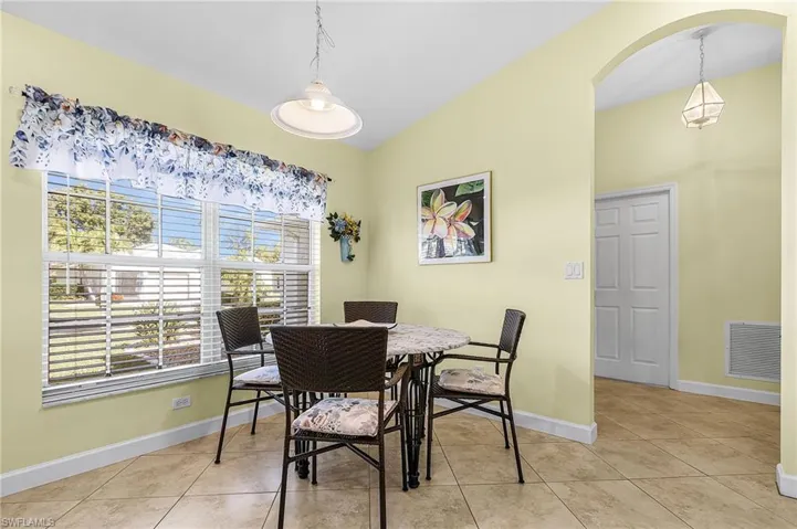 Dining room with arched walkways, vaulted ceiling, and light tile patterned floors