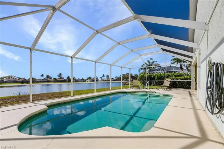 Outdoor pool with a sunroom, glass enclosure, a water view, a residential view, and a patio