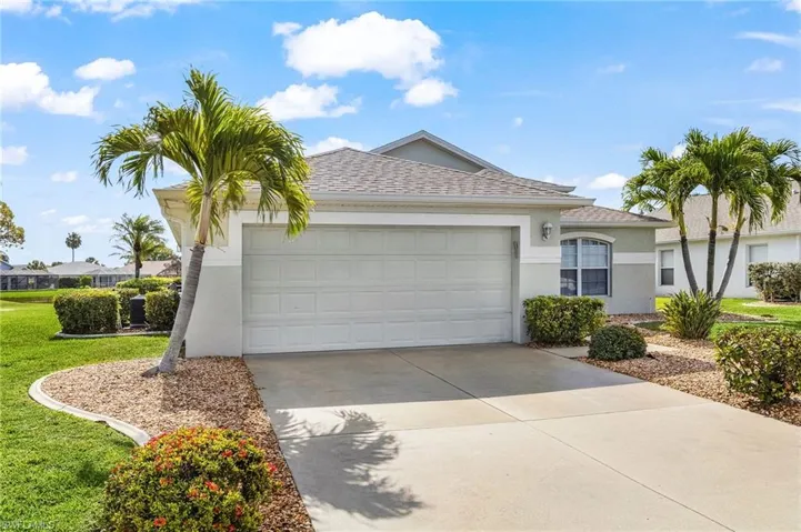 Ranch-style house featuring an attached garage, driveway, stucco siding, a shingled roof, and a front lawn