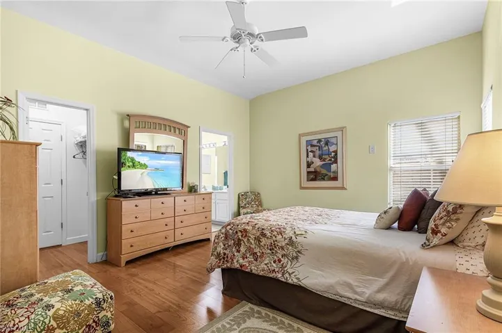 Bedroom with hardwood / wood-style floors, ceiling fan, and ensuite bath