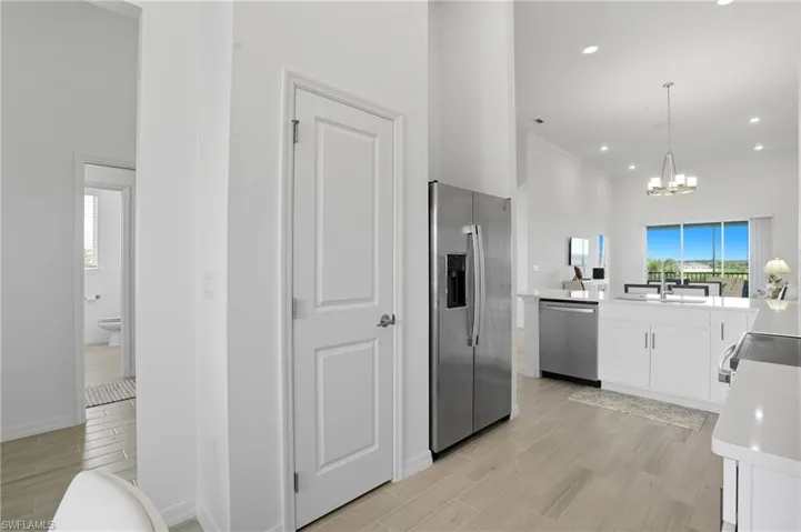 Kitchen with wood finish floors, appliances with stainless steel finishes, white cabinets, light stone counters, and recessed lighting
