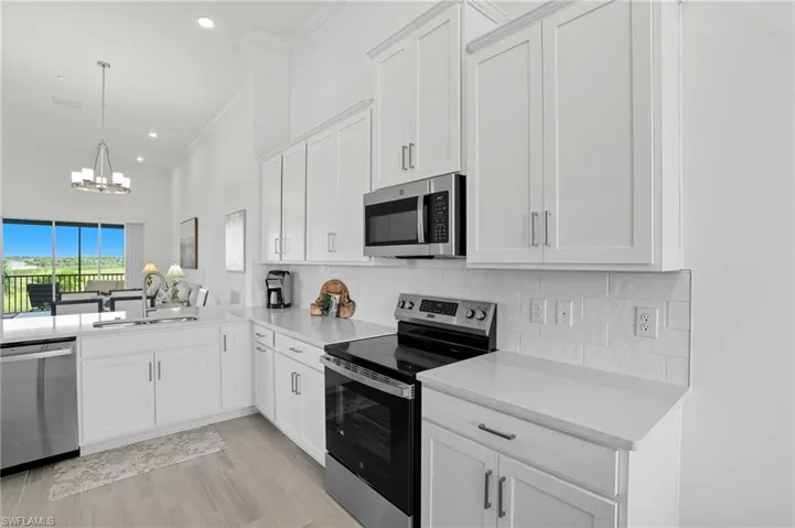 Kitchen featuring stainless steel appliances, white cabinets, a chandelier, decorative backsplash, and recessed lighting
