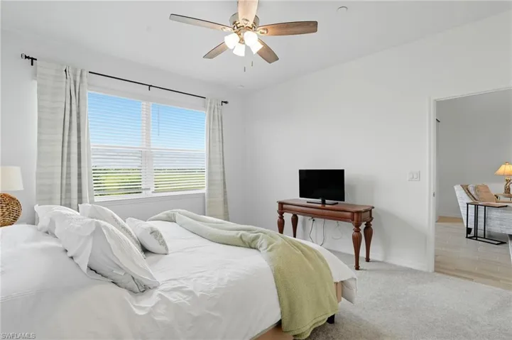 Carpeted bedroom featuring ceiling fan and baseboards