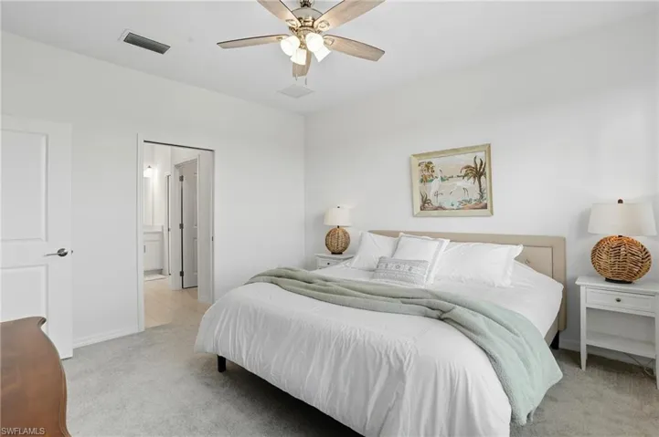 Bedroom with light carpet, a ceiling fan, and ensuite bath