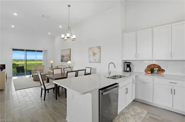 Kitchen with stainless steel dishwasher, white cabinets, a peninsula, wood tiled floors, and open floor plan