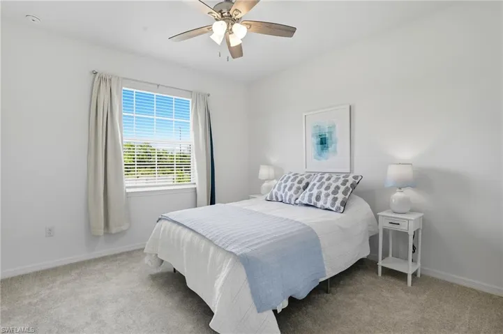 Bedroom with light colored carpet and a ceiling fan