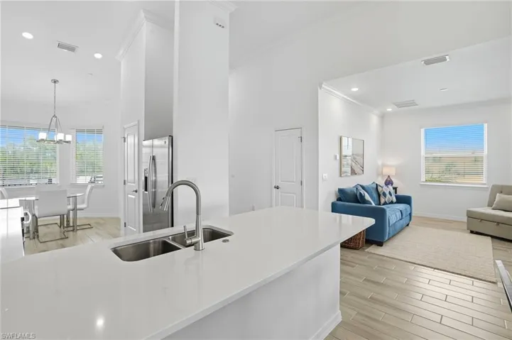 Kitchen featuring wood tiled floors, decorative light fixtures, open floor plan, ornamental molding, and recessed lighting