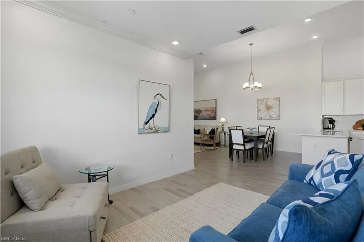 Living area featuring light wood finished floors, recessed lighting, crown molding, and a chandelier