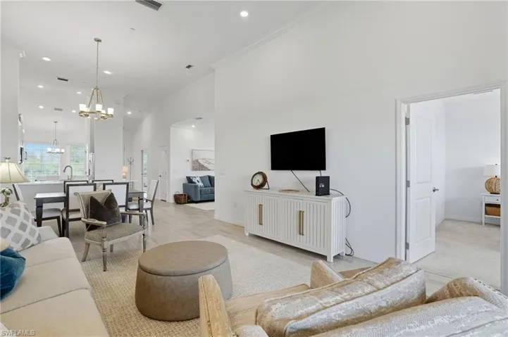 Living room featuring a chandelier, a high ceiling, recessed lighting, crown molding, and light wood-type flooring