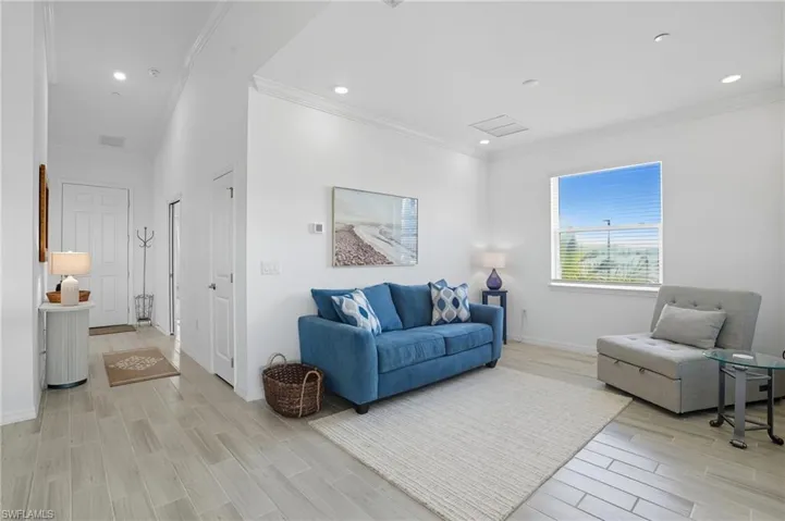 Living room featuring wood finish floors, ornamental molding, and recessed lighting