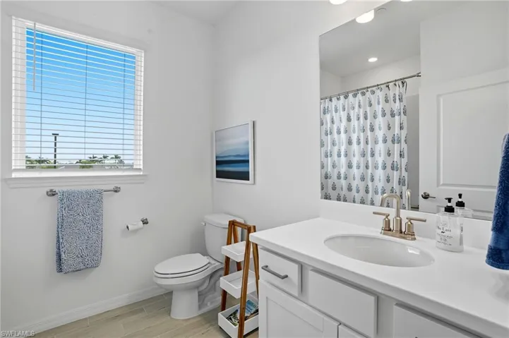 Bathroom with vanity, a shower with shower curtain, and wood finish floors