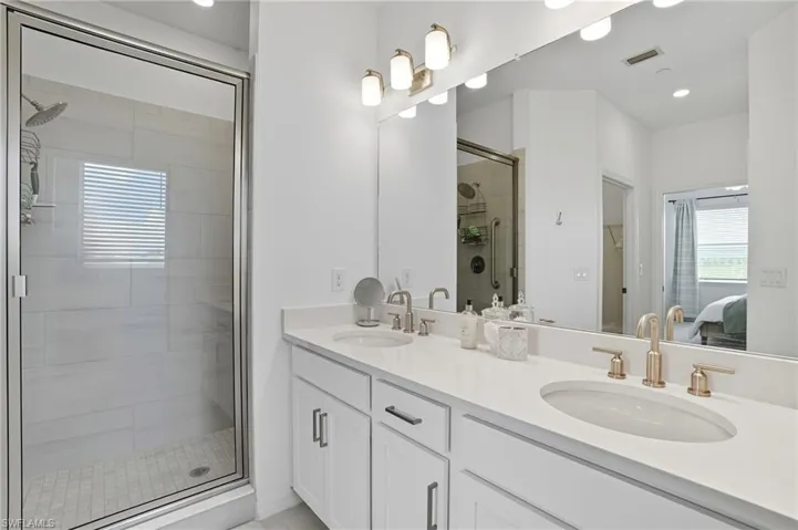 Ensuite bathroom featuring a stall shower, double vanity, recessed lighting, and light tile patterned floors