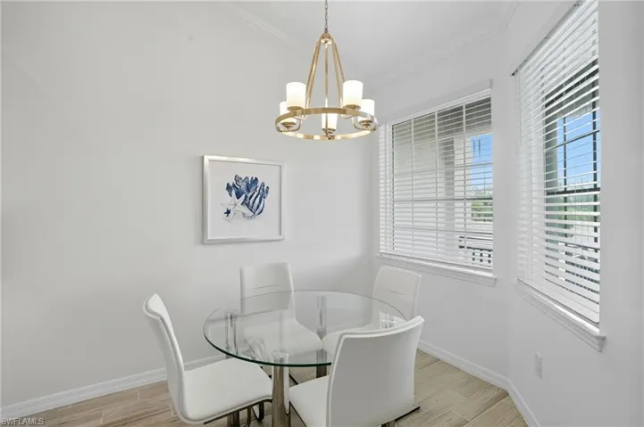 Dining area featuring ornamental molding, light wood-style floors, and a chandelier